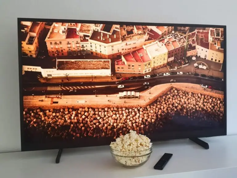 Televízor, ovládač a miska na bielej skrinke.