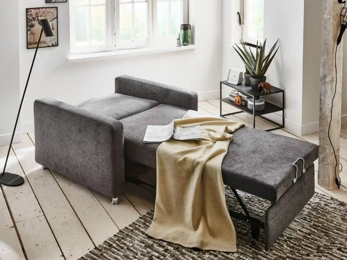 Rozkladateľné kreslo Potter s dekou a knihou, ako typický príklad hygge.
